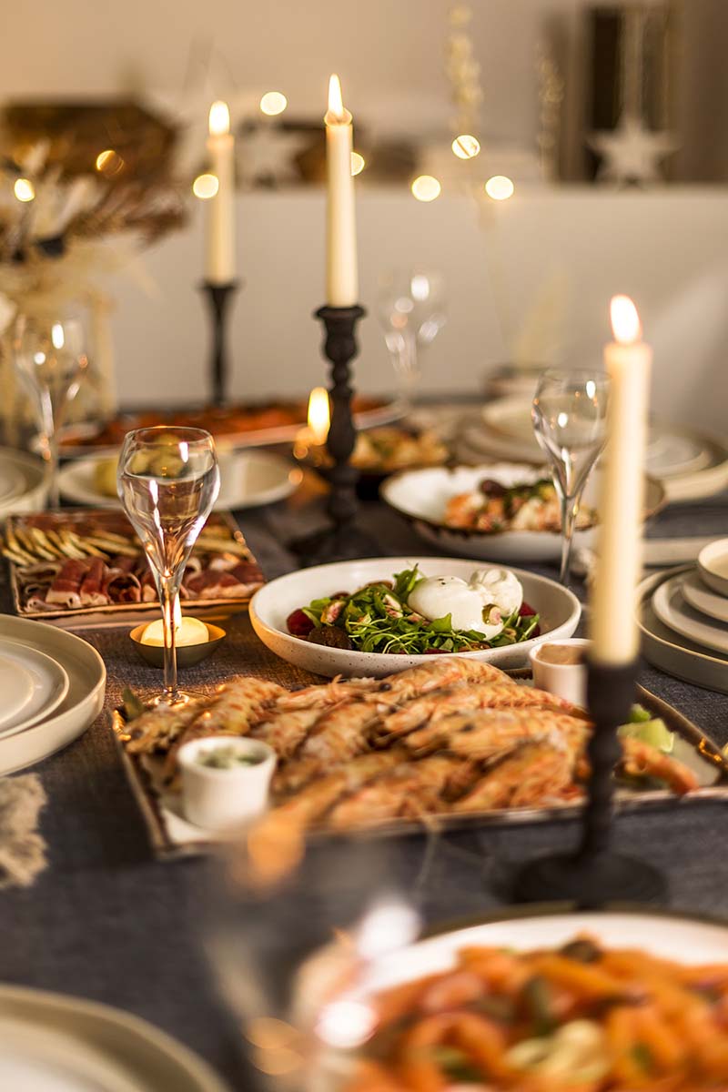 Mesa de Nochevieja con velas, langostinos y platos para compartir